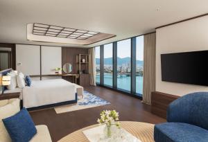a hotel room with a bed and a flat screen tv at TUI BLUE Han River in Danang