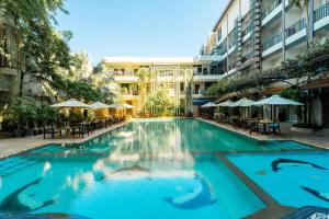 a swimming pool in a building with tables and umbrellas at Lé Blend Residence in Krong Poi Pet
