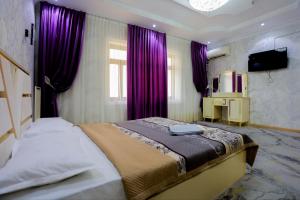 a bedroom with a bed with purple curtains and a television at Family Hotel in Khujand
