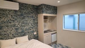 a bedroom with a bed and a wall with a wallpaper at ガジュマル House in Tonosho