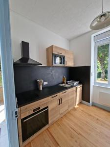 a kitchen with wooden cabinets and a black counter top at Appartement avec jardin privé à 5 min du Cheylard & Dolce Via - Vacances natures, vélo & randos in Accons