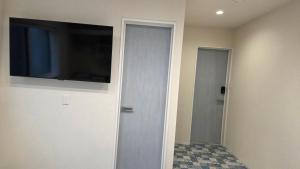 a hallway with a door with a flat screen tv at ガジュマル House in Tonosho