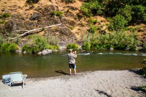a boy standing on a beach near a river at Russian River Camping Resort One-Bedroom Cabin 2 in Cloverdale