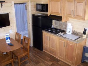 a kitchen with a black refrigerator and a table with chairs at Snowflower Camping Resort Cottage 7 in Emigrant Gap
