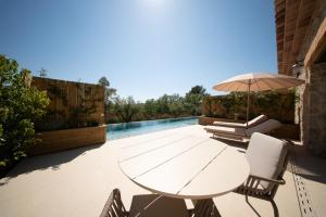 a white table with chairs and an umbrella on a patio at La Bastide des Rameaux - Boutique Hôtel & Spa in Callas
