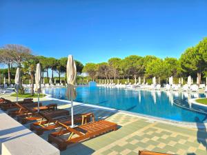 a large swimming pool with lounge chairs and umbrellas at Sunny Beach Penthouse - 216 in Draç