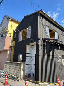 a black house with its door open on a street at HOTEl MOTO in Oshima