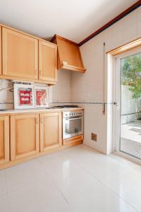a kitchen with wooden cabinets and a large window at Casa Lagoa Azul in Foz do Arelho