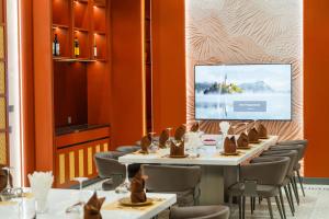 a dining room with tables and chairs and a screen at Lé Blend Residence in Krong Poi Pet