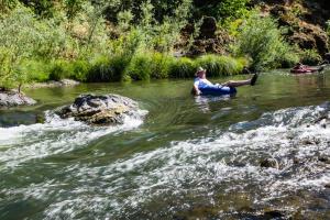 Un uomo seduto in acqua in un fiume di Russian River Camping Resort Studio Cabin 4 a Cloverdale