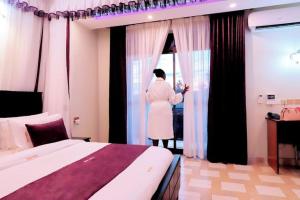a woman standing in a bedroom looking out the window at Rubax motel mbarara in Mbarara