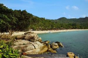 a beach with large rocks and a beach with people at Cheaper Room in Surat Thani