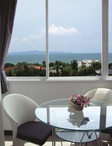 a glass table with chairs and a vase of flowers at Grand Residence Jomtien in Jomtien Beach