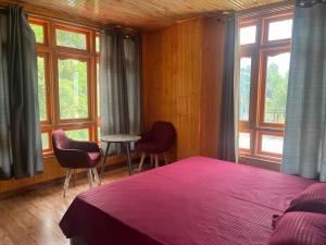 a bedroom with a bed and two chairs and windows at DELTA Inn HOMESTAY in Khashdhār