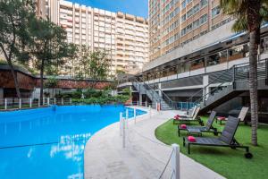 a large swimming pool with chairs and a building at Meliá Castilla in Madrid