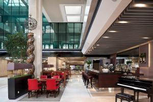 a restaurant with a piano and a bar with red chairs at Meliá Castilla in Madrid