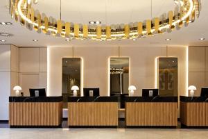 a lobby with a row of desks and a chandelier at Meliá Avenida América in Madrid