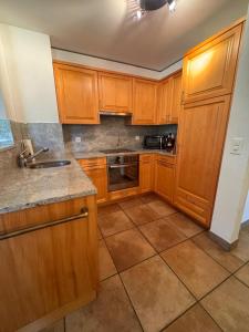 a kitchen with wooden cabinets and a tile floor at Tgèsa Staziun in Sedrun +4 photos