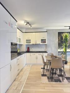 a kitchen with white cabinets and a table and chairs at Prishtina Escape Apartments - Luxury & Modern Apartment in Prishtinë