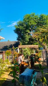 a man sitting at a table in front of a house at pesisircottage & stay in Selong Belanak