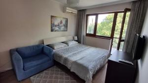 a bedroom with a bed and a blue chair at Villa Detelina Balchik in Balchik