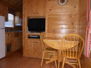 Oakzanita Springs Camping Resort Cabin 1 في Descanso: مطبخ مع طاولة وكرسيين وتلفزيون