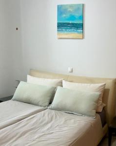 a bed with white pillows and a picture of the ocean at Vista Dourada in Porto Santo