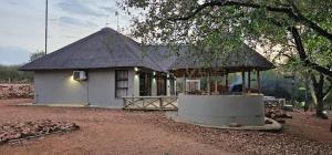 a small white house with a thatched roof at Pata Pata House in Marloth Park