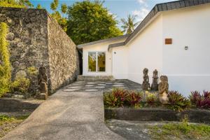 a white house with a stone wall and a driveway at Villa Panorama in Nusa Penida