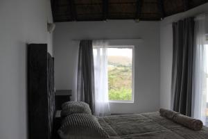 a bedroom with a bed and a large window at Hole in the Wall - Unit H1 in KuGqangushe +23 photos