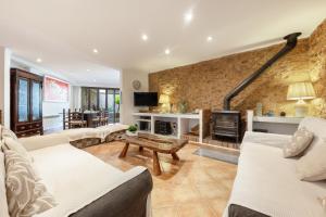 a living room with white furniture and a stone wall at Casa Horta Den Menut in Pollença