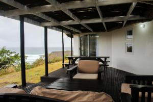 a deck with a table and a chair and the ocean at Hole in the Wall - Unit H1 in KuGqangushe