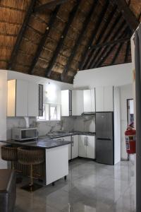 a kitchen with white cabinets and a black refrigerator at Hole in the Wall - Unit H1 in KuGqangushe