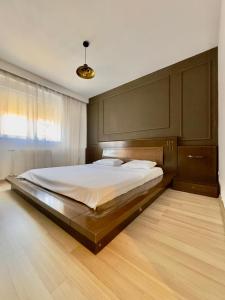 a bedroom with a large bed with a wooden headboard at Prishtina Escape Apartments - Luxury & Modern Apartment in Prishtinë