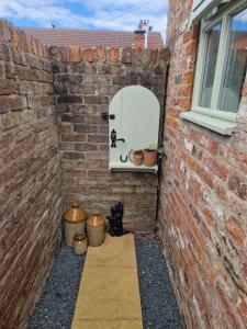 a brick wall with a window and a cat sitting in a courtyard at The Stables Annexe in Patrington +3 photos