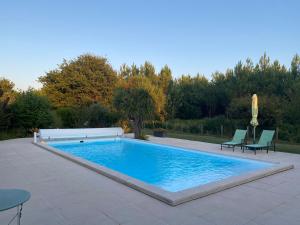 a swimming pool with two chairs and a table at Villa Caplanne in Sanguinet