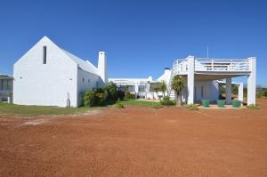 a white building on a dirt field next to a house at Hoekkraaltjie in Yzerfontein