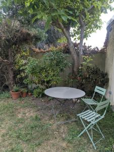a table and two chairs in a yard with a tree at Logement Indépendant - à proximité de Lille in Lambersart