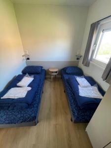 two beds in a small room with a window at Waddenlodge Premium in Harlingen