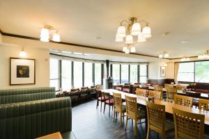 a dining room with tables and chairs and windows at Hakuba Yamano Hotel in Hakuba