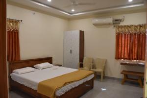 a bedroom with a bed and a table and chairs at PVR Grand in Tirupati