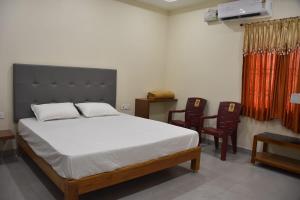 a bedroom with a bed with two chairs and a table at PVR Grand in Tirupati