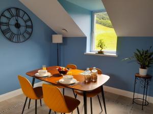 a dining room with a table with chairs and a clock at The Old Saw Mill in Llangunllo