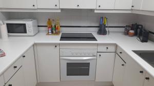 a white kitchen with a stove and a microwave at Los Vetones in Ciudad-Rodrigo