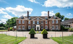 a large brick house with two trees in front of it at Chilston Park Hotel in Maidstone