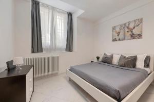 a white bedroom with a bed and a television at Casa Sole Porlezza in Porlezza