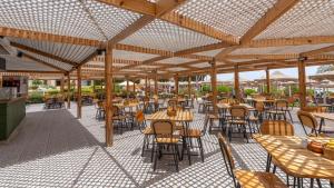 an outdoor patio with tables and chairs and wooden umbrellas at PLM hotel Prima Life Makadi in Hurghada