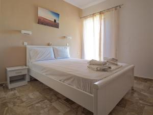 a white bed in a room with a window at Rose Garden in Melíkia