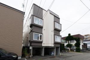 a white and black house with windows at Gran Form Kita 12-jo in Kita-sanjō
