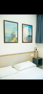 two beds in a room with two pictures on the wall at Sperlonga Center Holiday in Sperlonga